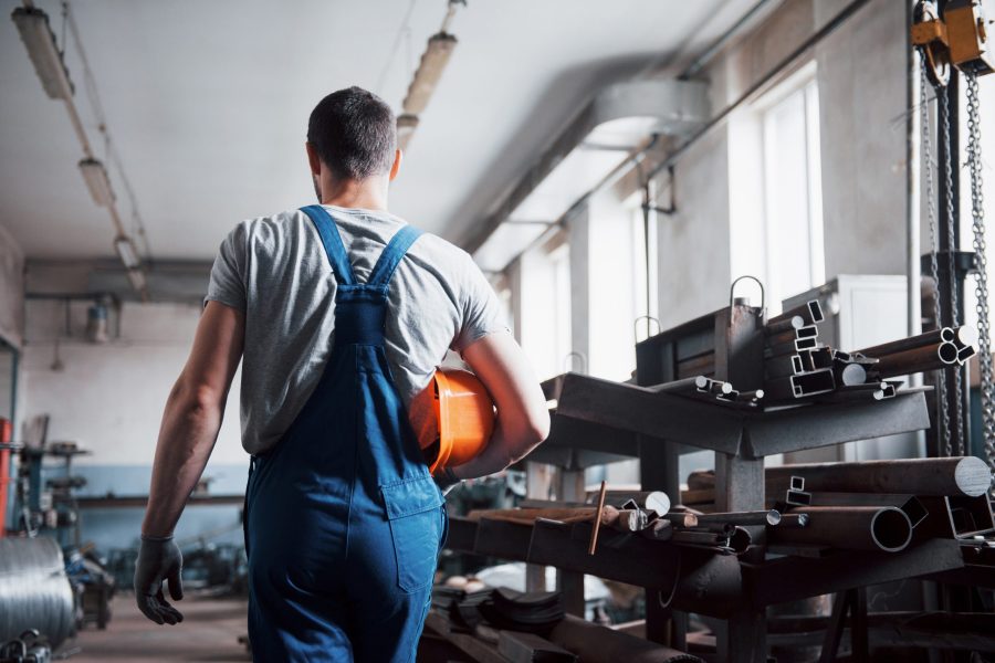 Portrait of a young worker in a hard hat at a large waste recycling factory. The engineer monitors the work of machines and other equipment.